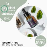 Egy 10ml-es üveg CBD Europe 10% teljes spektrumú Kannabisz olaj (1000mg) cseppentővel egy fehér felületen ül zöld levelek, egy tál fehér por és egy kanál olaj között. Szöveges megjegyzések teljes spektrumú, 100% organikus CBD olaj.