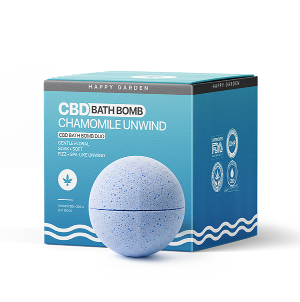 Egy kék pöttyös fürdőbomba pihen egy teáskék és kék doboz előtt, amelyen a "Kamilla Unwind - CBD Fürdőbomba Duo - 100mg CBD" felirat áll, kiemelve a gyengéd virágillatot és a nyugtató CBD előnyeit.