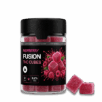 A „Happy H Gummies Raspberry (Málna) – 10 mg/db Strong Edition, 12 db” feliratú üvegben cukrozott málnakockák és friss málna látható, az üveg mellett pedig két gumicukorka. A címke 12 darabot és erős hatást jelöl.