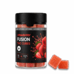 Egy „Happy H Gummies Strawberry (Eper) – 10 mg/db – Strong Edition, 12 db” feliratú üveg eperképekkel van díszítve. Mellette két piros, cukorral bevont gumicukorka látható. A címke szerint az üvegben 12 darab található, és magas a THC-tartalma.